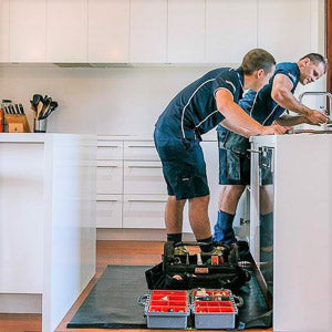 Plumber using a large tidy tradie work mat and wearing cleanboots