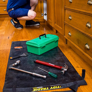 A professional electrician puts tools on a tidy tradie work mat and wears cleanboot covers.