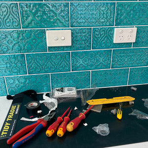 An electrician working over a tidy tradie work mat to protect the kitchen bench top.